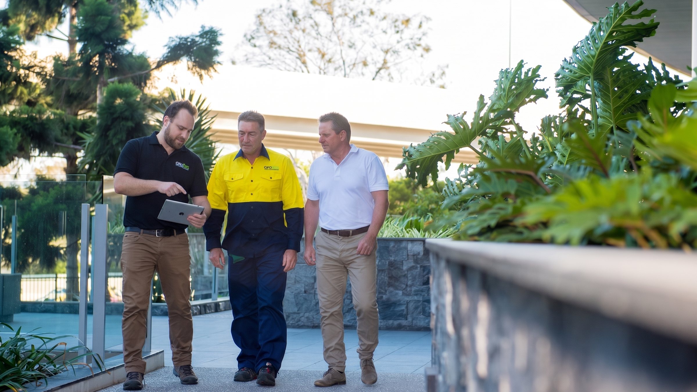 A Grolife team member walking a commercial site with a crew member and client, iPad in hand for the site walk-through