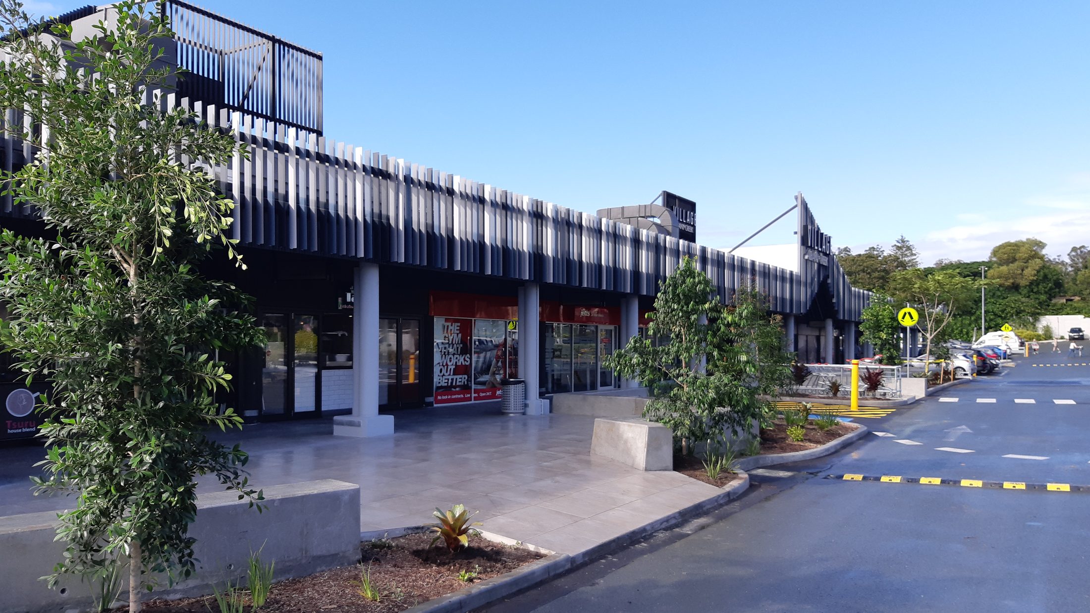 A finished commercial landscape constructed by Grolife — paved forecourt, retaining walls and established garden beds
