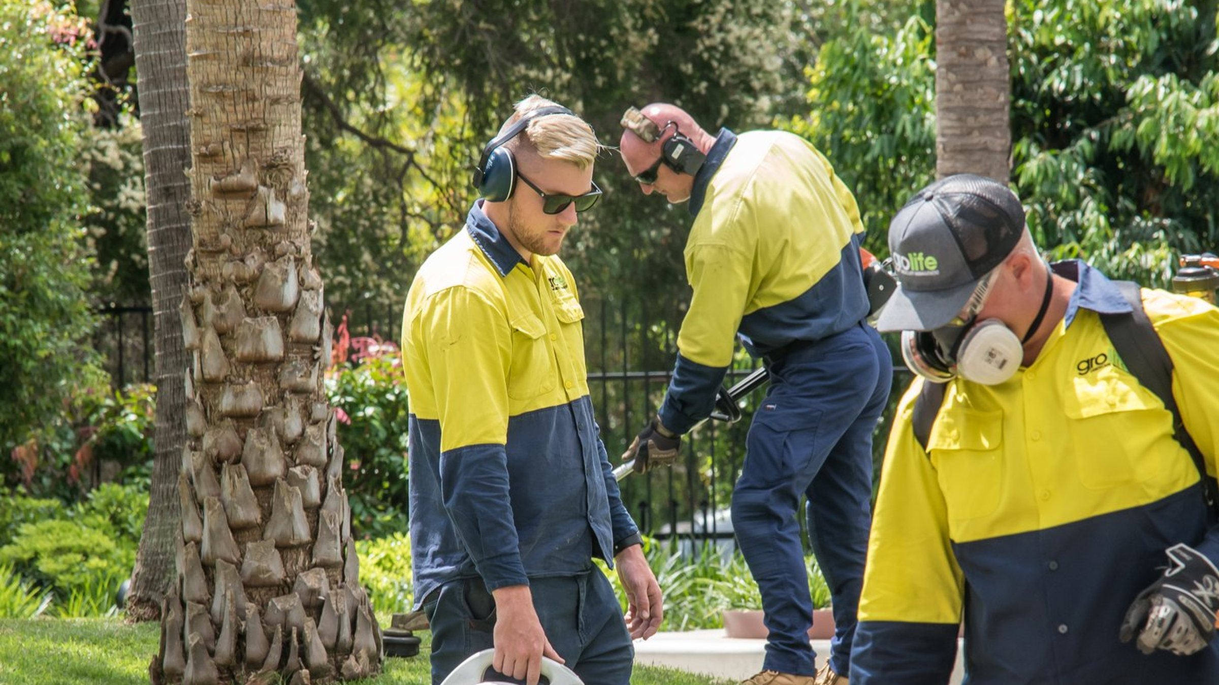 Grolife crew working on a commercial landscape site in South East Queensland — battery-electric kit, hi-vis, on the job