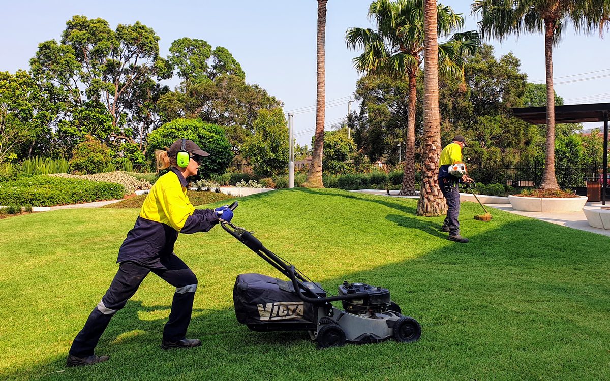 Grolife crew operating a Victa walk-behind mower on a commercial lawn