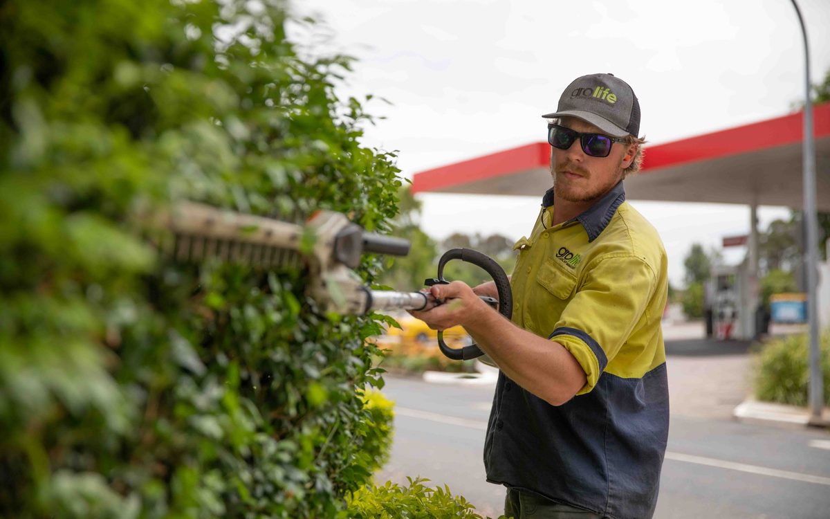 Grolife crew member clearing a commercial pathway with a leaf blower